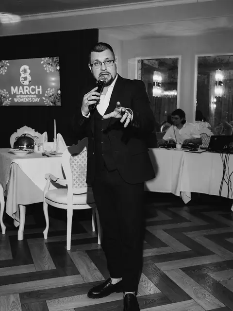 Чорно-біле фото ведучого з мікрофоном у залі ресторану