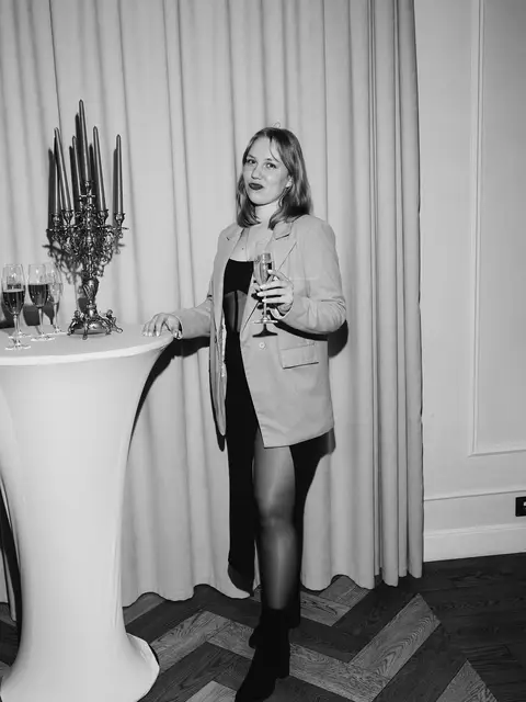 Чорно-білий портрет гості з келихом біля фотозони