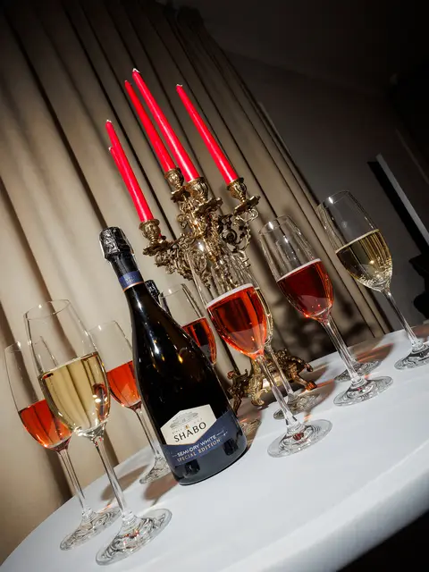 Келихи ігристого та пляшка вина на святковому столику зі свічками