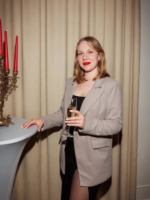 Гостя з келихом вина біля святкового столика зі свічками