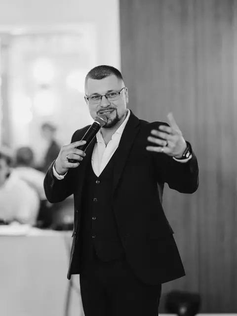 Чорно-біле фото ведучого з мікрофоном під час програми