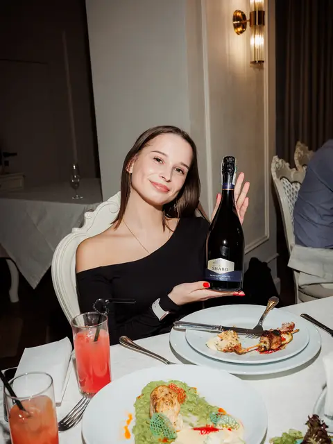 Дівчина за столом із коктейлями та стравами в ресторані